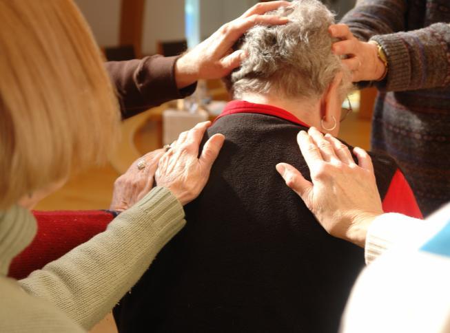 Hands laid on a person's head and shoulders in prayer