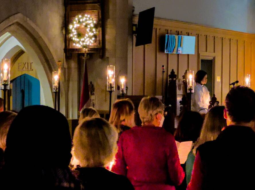 Candlelit Christmas service at St. Timothy's, with the congregation standing and the choir beside the Christmas tree